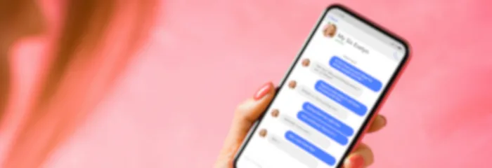 A hand holding a smartphone showing a chat thread of blue message bubbles