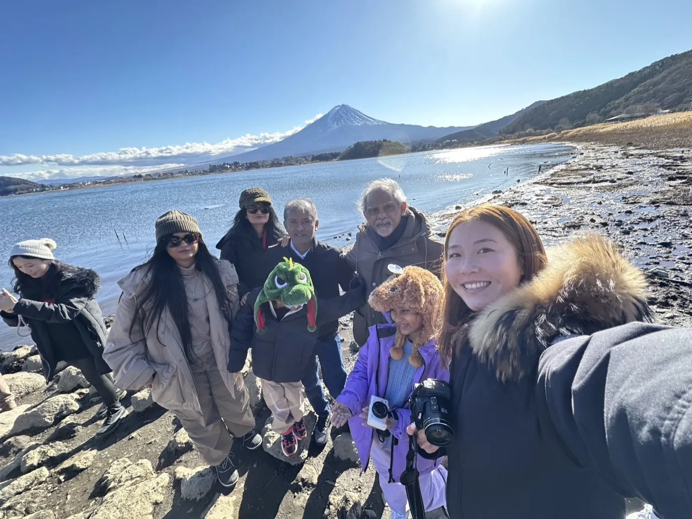 A family with their guide on the shore of a lake with Mt. Fuji behind them